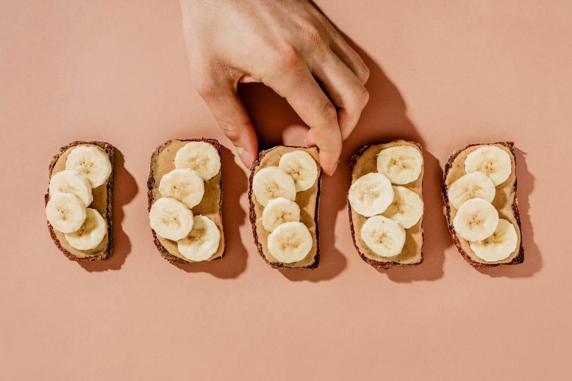 Hand Reaching For Peanut Butter Banana Toasts On Pink Seamless مجلة نقطة العلمية