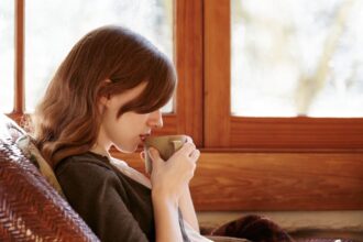 woman drinking tea on porch of log cabin إذا طال مرضك.. فإليك الأسباب التي تجعلك تمرض والعلاج! مجلة نقطة العلمية