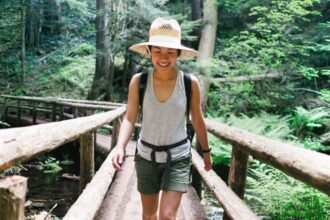 woman smiling while crossing a bridge on a hike 10٪ من الأشخاص سيعانون من نمو ما بعد الجائحة..فماذا يعني ذلك؟ مجلة نقطة العلمية