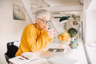 older woman sitting at her desk دراسة: تأخير التقاعد قد يكون المفتاح لعقل أكثر حدة مجلة نقطة العلمية