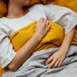 unrecognizable woman sleeping in bed at home ماهي العلاقة بين اوقات النوم وصحة القلب؟ مجلة نقطة العلمية