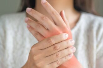 woman holding wrist أسوأ طعام يمكنك تناوله إذا كنت مصابًا بالتهاب المفاصل وفقا لخبراء التغذية! مجلة نقطة العلمية