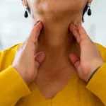 mature woman touching hands to her neck checking thyroid health 5 طرق طبيعية لإعادة شحن صحة الغدة الدرقية مجلة نقطة العلمية